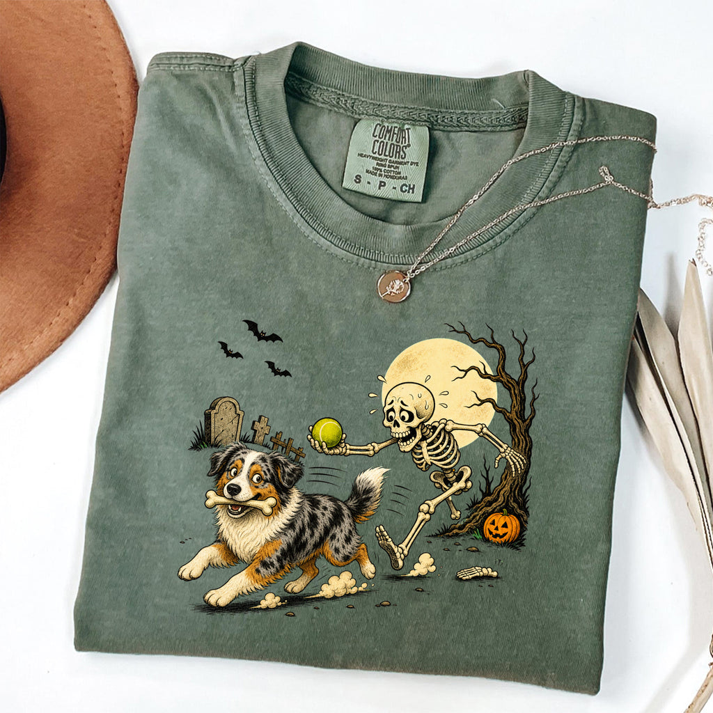 Skeleton Chasing Aussie Halloween Shirt T-Shirt in Moss, vintage Halloween graphic tee with an Australian Shepherd and skeleton