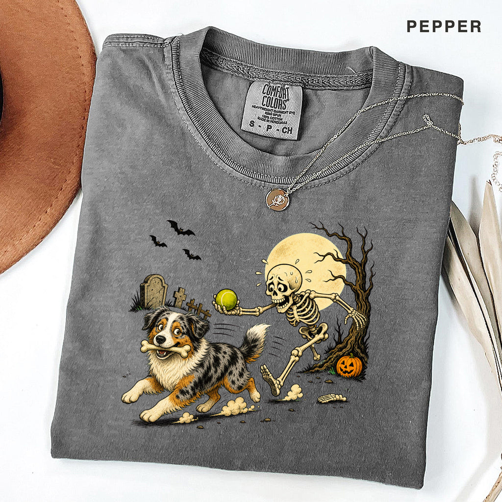 Skeleton Chasing Aussie Halloween Shirt T-Shirt in Pepper, vintage Halloween graphic tee with an Australian Shepherd and skeleton