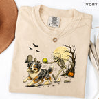 Skeleton Chasing Aussie Halloween Shirt T-Shirt in Ivory, vintage Halloween graphic tee with an Australian Shepherd and skeleton